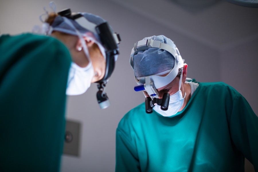 Two surgeons wearing surgical loupes and caps during an operation in an operating room